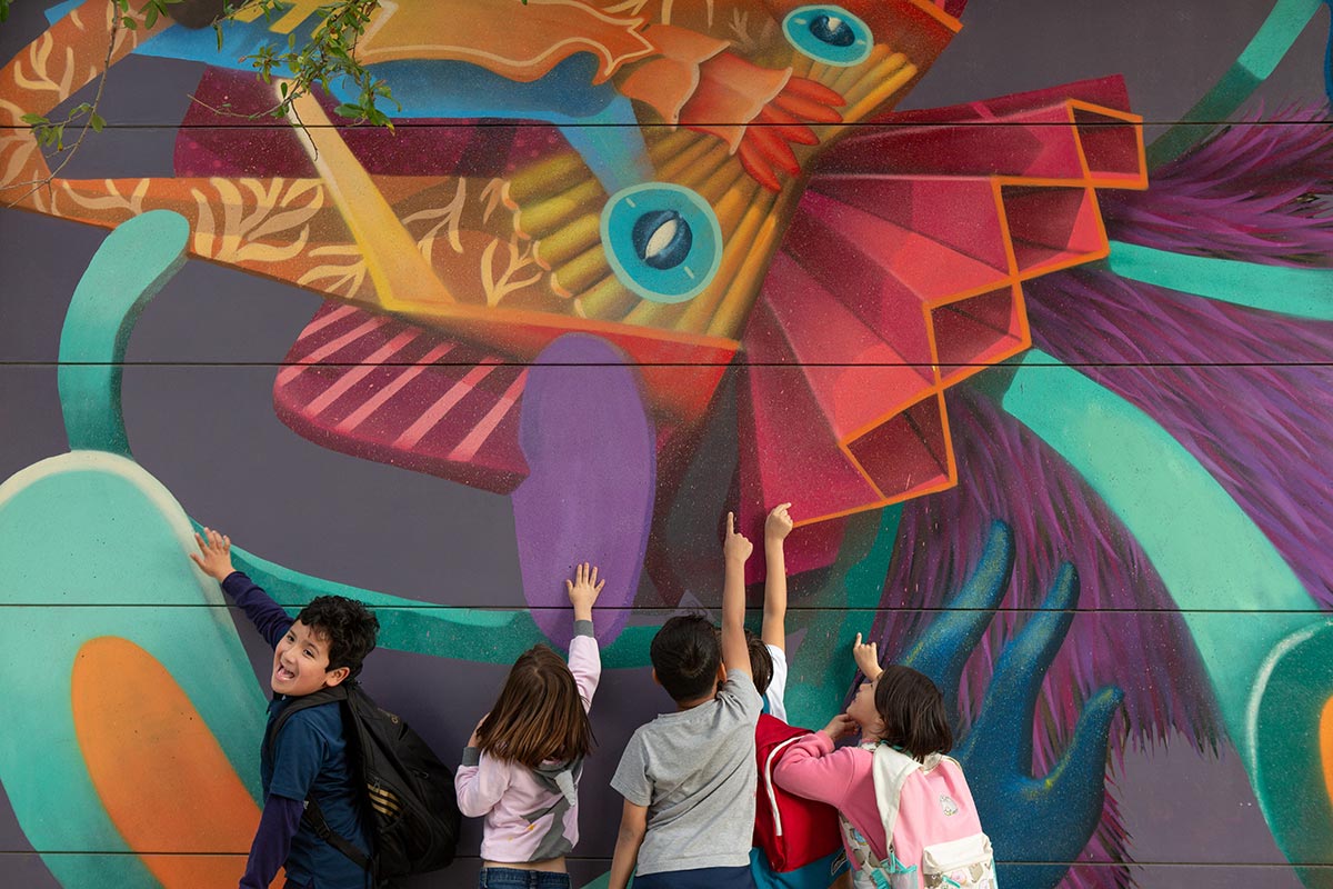 Elementary students point at mural